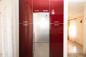 einem Kühlschrank aus Edelstahl in einer Küche mit roten Schränken in der Unterkunft Villas Gregory in Syvota