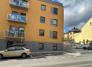 un bâtiment jaune avec une voiture garée dans un parking dans l'établissement Apartment EDIAS, à Banská Bystrica