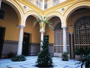 a building with palm trees in a courtyard at Conteros Centro Apartment in Seville