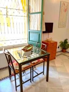 una mesa de cristal y una silla en una habitación con ventana en Conteros Centro Apartment, en Sevilla