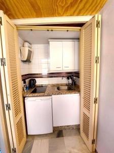 una pequeña cocina con armarios blancos y fregadero en Conteros Centro Apartment, en Sevilla