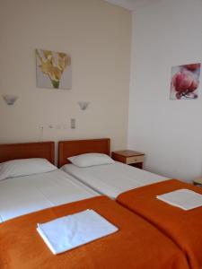 Efstratios Hotel في لوترا إديبسو: سريرين في غرفة نوم مع ملاءتين بيضاء