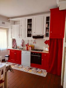 a red kitchen with white cabinets and a stove at Dandelion home Viareggio centro in Viareggio