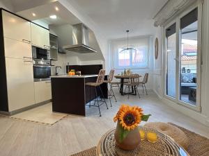 a kitchen and living room with a vase with a sunflower at Ático Luz y Mar in Cambados