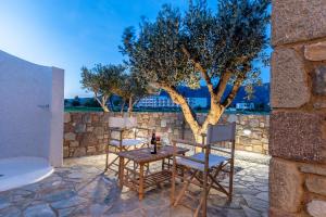 una mesa y sillas en un patio con un árbol en Vista Mare 100 Meters to Beach with BBQ, en Kardamaina