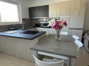 una cocina con una mesa con un jarrón de flores. en Marsaxlokk Modern Apartment, Large Backyard, en Marsaxlokk