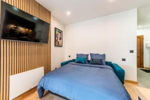 a bedroom with a blue bed with a tv on the wall at Studio The Greatest in Moutiers