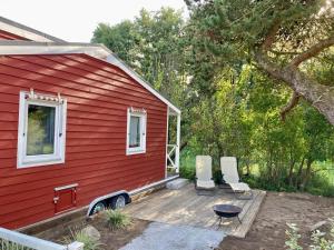 ein rotes Haus mit zwei Stühlen und einem Tisch auf einer Terrasse in der Unterkunft Tiny House am Meer in Heringsdorf