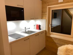 a kitchen with a sink and a microwave at Chalet L'Adret, 3,5 pièces dans les combles. in Gryon