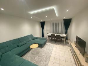 于南格100m2 3chambres 5km du Carnaval de BASEL Free Wifi的客厅里有一张绿色的沙发和一张桌子