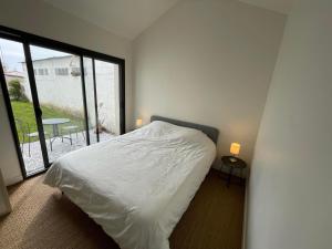um quarto com uma cama branca e uma grande janela em Maison 4 chambres - 8/10 personnes, proche mer em Brem Sur Mer