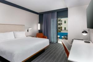 ゲインズビルにあるCourtyard by Marriott Gainesville GAのベッドとデスクが備わるホテルルームです。