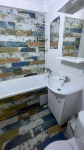 ein Badezimmer mit Waschbecken, Badewanne und Toilette in der Unterkunft Квартира между правым и левым берегом, рядом с набережной на улице Габдуллина in Astana + 14 Fotos