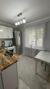 eine Küche mit weißen Schränken und einem Tisch darin in der Unterkunft Квартира между правым и левым берегом, рядом с набережной на улице Габдуллина in Astana