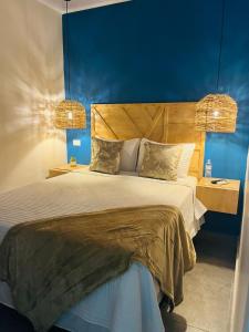 1 dormitorio con 1 cama grande y pared azul en WE Hotel, La Lima, en La Lima