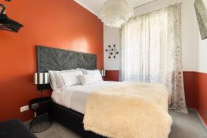 a bedroom with orange walls and a bed with white pillows at Cozy apartment Gianicolense 3bdr in Rome