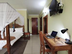 Schlafzimmer mit einem Bett und einem Schreibtisch mit einem Laptop in der Unterkunft New Safari Hotel 