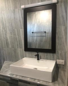 un lavandino bianco in un bagno con specchio di แครินโฮมสเตร์ a Koh Lone