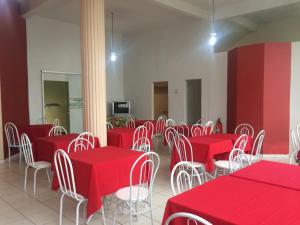 a dining room with red tables and white chairs at Hostel Rotor in Ouro Branco