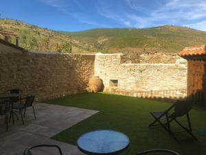 eine Terrasse mit Stühlen, Tischen und einer Steinmauer in der Unterkunft Hotel Rural El Rincón de Marta in Yanguas