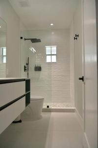 a white bathroom with a shower and a toilet at Luxury contemporary hidden gem in Lehigh Acres