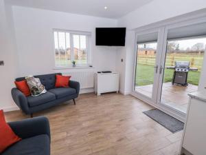 ein Wohnzimmer mit einem Sofa und einem Flachbild-TV in der Unterkunft Walnut Lodge in Ashbourne