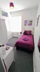 - une chambre avec un lit violet et une table dans l'établissement The Castleton, à Blackpool
