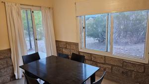 a dining room with a table and two windows at Entre Montañas in Potrerillos