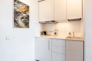 una cucina con mobili bianchi e un lavandino di Kaunas apartments near Bus station a Kaunas