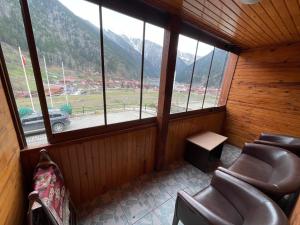 a room with a group of chairs and windows at Uzungöl Bikka Pansiyon in Uzungöl