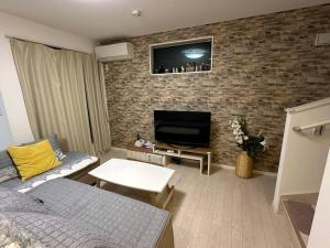 a living room with a couch and a tv on a brick wall at 一期一会Ⅱ in Osaka