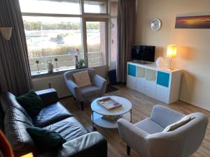 a living room with a couch and chairs and a tv at Texel-De Koog 116 in De Koog