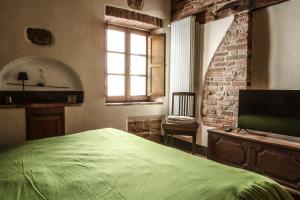 una camera con un letto verde e un muro di mattoni di IL MAGNIFICO a Montepulciano