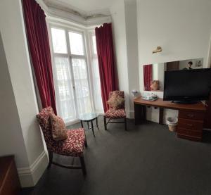 a living room with a television and a desk and chairs at The Embassy Hotel in Great Yarmouth