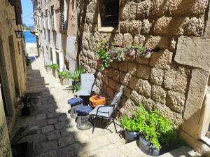 un callejón con sillas, una mesa y una pared de piedra en Fidelissima Palace en Korčula