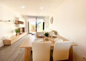 a dining room with a wooden table and white chairs at Atico Solarium La Cala in Miami Platja