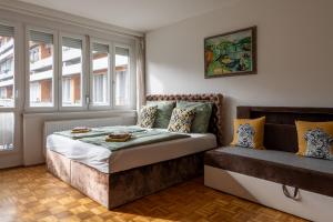 a bed and a couch in a room with windows at ROOF TERRACE access CASTLE dst. PARLIAMENT 1stop in Budapest