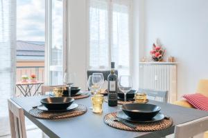 Una mesa de comedor con vasos y una botella de vino. en Appartamento Centrale Con Parcheggio e Wi-Fi Gratuito AC, en Alba