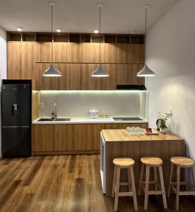 a kitchen with a refrigerator and a table with stools at La Mer House Đà Lạt in Ấp Ða Lợi