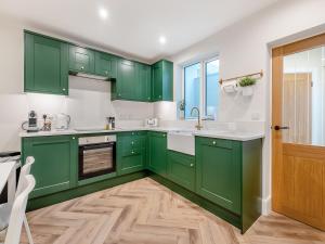 a green kitchen with white walls and wooden floors at Ivy Cottage in Belper