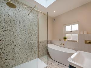 a bathroom with a shower and a tub and a sink at Ivy Cottage in Belper