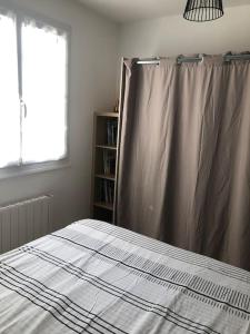 a bedroom with a bed with a curtain and a window at Appartement Lumineux-Coeur de ville & plages in Concarneau +9 photos