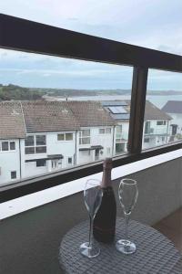 a bottle of wine and two glasses on a table at Stylish Saundersfoot 2-Bed Seaview Apartment, Balcony & Parking in Pembrokeshire