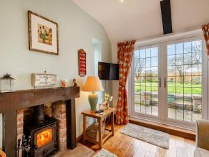 a living room with a fireplace and a window at Little Crawfish Cottage in Thursford