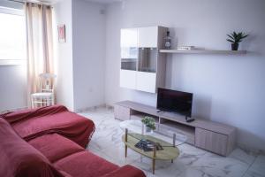 a living room with a red couch and a tv at Cova da Iria 5 in Tal-Pietà