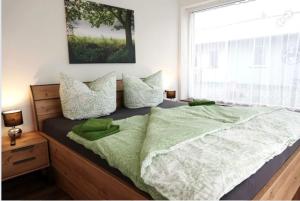 ein Schlafzimmer mit einem Bett mit grüner Bettwäsche und einem Fenster in der Unterkunft Ferienwohnungen zum Dubener Kuckuck in Luckau + 10 Fotos