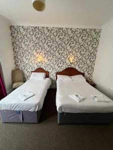 dos camas sentadas una al lado de la otra en una habitación en The Embassy Hotel, en Great Yarmouth