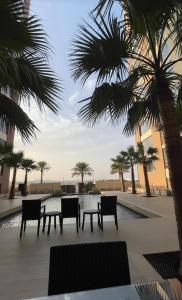a patio with chairs and a table and palm trees at Saraya Al Olaya Tower family house in Al Khobar