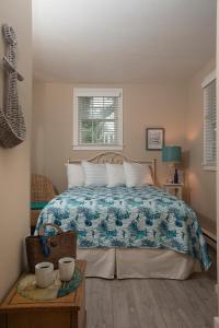 1 dormitorio con 1 cama con manta azul y blanca en Ship's Knees Inn, en East Orleans