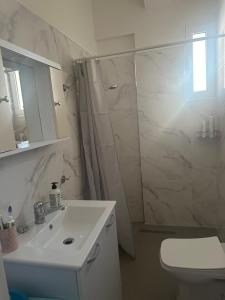 een witte badkamer met douche en wastafel bij Vlora Central & Comfy Apartment in Vlorë